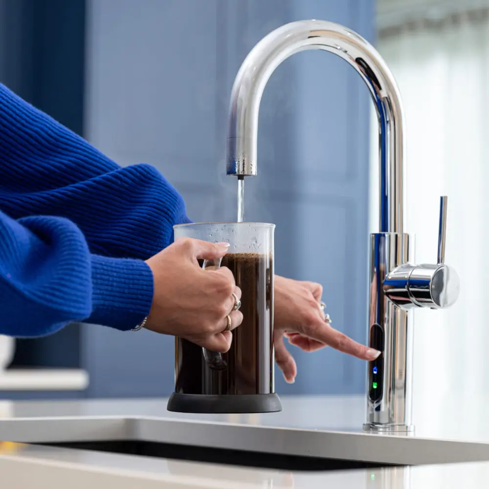 A Person Pouring Boiling Water From A Tap Into A Cafetiere