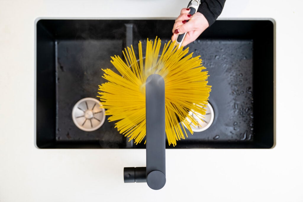 Aquatap Ultimo Boiling Water Tap Dispensing Instant Hot Water Into A Saucepan For Pasta Preparation, Top View Kitchen Scene